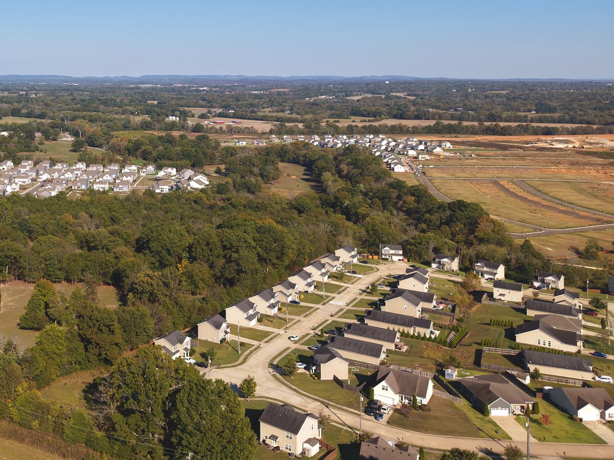 Aerial view of homes along a curving street with woods and fields beyond in Columbia, Tennessee.