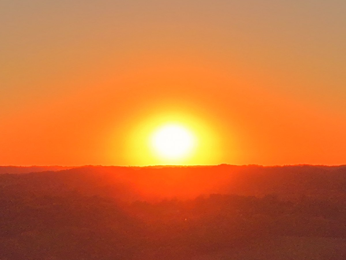 Aerial view of the sun setting over a wooded ridge in Middle Tennessee.